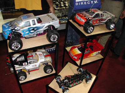 Cars and trucks on display at Schumacher's booth.  The Menace 21 trucks sit at the top of the podium, along with the Nitro XTR 3E, the Nitro Fusion, and at the bottom, the MI2 prototype. (Click to enlarge)